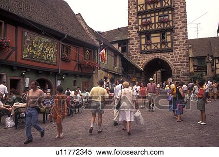 Stock Photography -  France, Alsace, Riquerwihr, Haut-Rhin, Europe, wine region, outdoor cafT, People walking on the cobbled streets in the picturesque village of Riquerwihr in the wine region of Alsace.. Fotosearch
