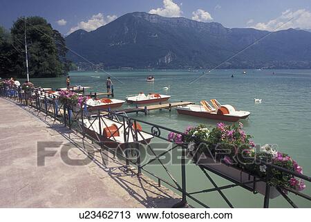 Stock Image -  France, Annecy, Haute-Savoie, Rhone-Alpes, Europe, Paddleboats docked on the waterfront of Lake Annecy (Lac d' Annecy) surrounded by mountains in Annecy.. Fotosearch