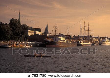 Germany, Lubeck, Schleswig-Holstein, Baltic Sea, Europe, Boats docked in the Hansahafen (harbor) in Lubeck. Two people rowing a scull. View Large Photo Image Stock Image - Germany, Lubeck, Schleswig-Holstein, Baltic Sea, Europe, Boats docked in the Hansahafen (harbor) in Lubeck. Two people rowing a scull.. Fotosearch