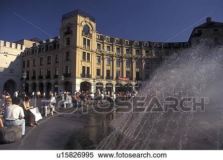 Stock Photography -  Germany, Munich, Bavaria, Munchen, Europe, People sitting around the fountain in the public plaza in downtown Munich.. Fotosearch