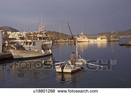 Stock Photo -  Greece, Paros, Greek Islands, Naoussa, Cyclades, Europe, Fisherman rowing fishing boat in Naoussa Harbor in the early morning on Paros Island on the Aegean Sea.. Fotosearch