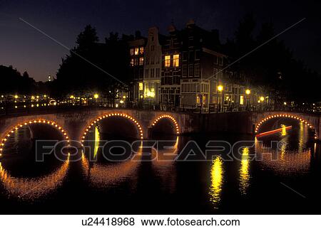 Holland, Amsterdam, Netherlands, Noord-Holland, Europe, Bridge with arches illuminated at night on a canal in Amsterdam. View Large Photo Image Stock Photo - Holland, Amsterdam, Netherlands, Noord-Holland, Europe, Bridge with arches illuminated at night on a canal in Amsterdam.. Fotosearch