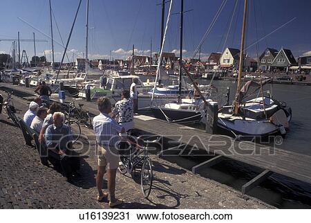 Stock Image -  Holland, Volendam, Netherlands, Noord-Holland, Europe, People relaxing on the waterfront on the harbor on Markermeer in the town of Volendam.. Fotosearch