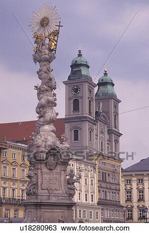 Stock Image -  Linz, Austria, The Danube Valley, Oberosterreich, Pillars of the Holy Trinity at Hauptplatz and Old Cathedral in downtown Linz.. Fotosearch