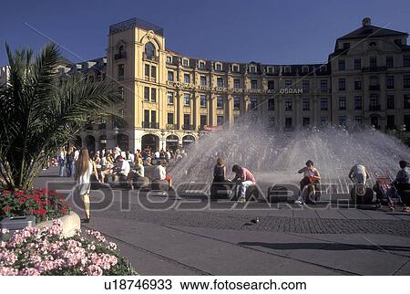 Munich, Germany, Bavaria, Munchen, Europe, People sitting around the fountain in the public plaza in downtown Munich. View Large Photo Image Stock Image - Munich, Germany, Bavaria, Munchen, Europe, People sitting around the fountain in the public plaza in downtown Munich.. Fotosearch