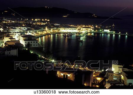 Stock Photo -  Mykonos, Greece, Greek Islands, Cyclades, Europe, Scenic view of Mykonos Harbor in the evening on the Aegean Sea.. Fotosearch