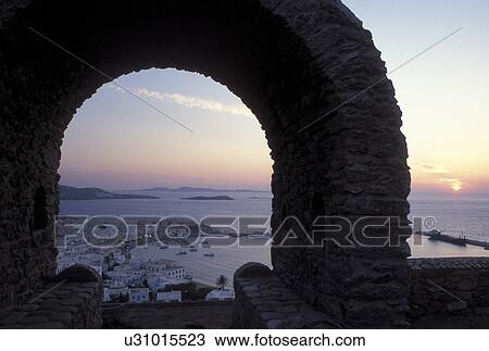 Mykonos, Greek Islands, Cyclades, Greece, Europe, Scenic view of Mykonos Harbor from a stone archway at sunset on the Aegean Sea. View Large Photo Image Stock Image - Mykonos, Greek Islands, Cyclades, Greece, Europe, Scenic view of Mykonos Harbor from a stone archway at sunset on the Aegean Sea.. Fotosearch