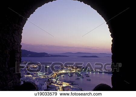 Mykonos, Greek Islands, Cyclades, Greece, Europe, Scenic view of Mykonos Harbor from a stone archway at sunset on the Aegean Sea. View Large Photo Image Stock Photo - Mykonos, Greek Islands, Cyclades, Greece, Europe, Scenic view of Mykonos Harbor from a stone archway at sunset on the Aegean Sea.. Fotosearch