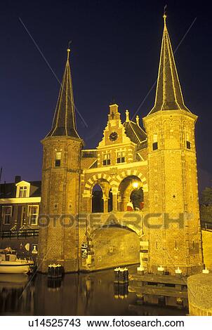 Stock Image -  Netherlands, Sneek, Holland, Friesland, Europe, Water Tower (1613) along the canal in downtown Sneek illuminated at night.. Fotosearch