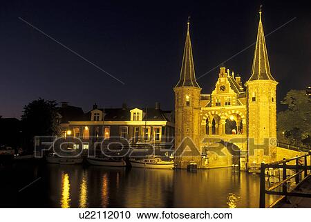 Stock Image -  Netherlands, Sneek, Holland, Friesland, Europe, Water Tower (1613) along the canal in downtown Sneek illuminated at night.. Fotosearch