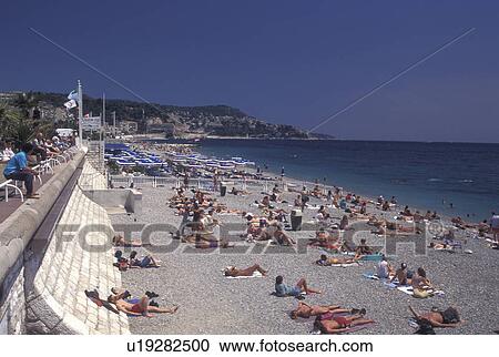 Stock Image -  Nice, Cote d' Azur, France, Provence, Alpes-Maritimes, Europe, Sunbathing on the beach along the Promenade des Anglais on the Mediterranean Sea in the city of Nice.. Fotosearch