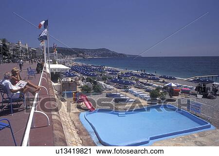Nice, France, beach, Cote d' Azur, Provence, Alpes-Maritimes, Europe, People sitting along the Promenade des Anglais looking out at the beach on the Mediterranean Sea in the city of Nice. View Large Photo Image Stock Image - Nice, France, beach, Cote d' Azur, Provence, Alpes-Maritimes, Europe, People sitting along the Promenade des Anglais looking out at the beach on the Mediterranean Sea in the city of Nice.. Fotosearch