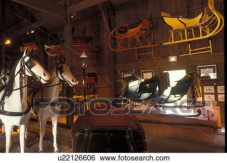 Stock Photograph -  NY, New York, Mumford, Horse-drawn carriages and sleighs displayed inside the Carriage Museum at Genesee Country Village & Museum. Fotosearch