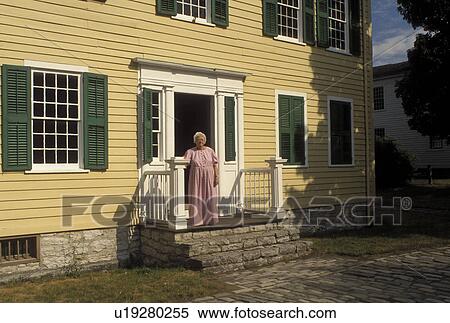 Stock Photography -  NY, New York, Mumford, Woman interpreter dressed authentic costume stands outside Hosmer's Inn at Genesee Country Village & Museum. Fotosearch