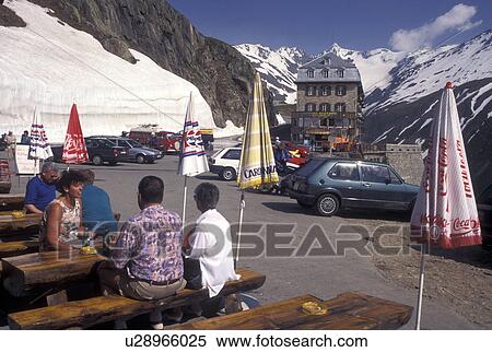 outdoor cafT, Switzerland, Valais, Alps, Belvedere, Furka Pass, People sitting at picnic tables outside a restaurant in the snow at the summit of the Furka Mountain Pass Road in the Swiss Alps in the summer. View Large Photo Image Stock Photography - outdoor cafT, Switzerland, Valais, Alps, Belvedere, Furka Pass, People sitting at picnic tables outside a restaurant in the snow at the summit of the Furka Mountain Pass Road in the Swiss Alps in the summer.. Fotosearch