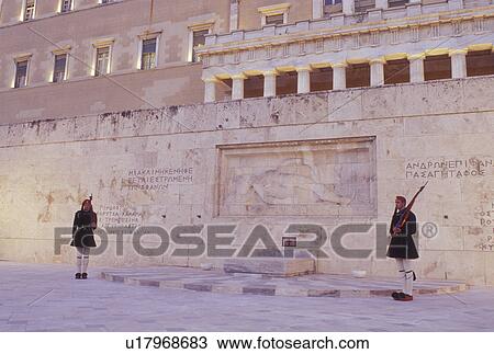 Stock Image -  Parliament, Athens, Greece, Europe, Guards of Honor (evzones) standing at the Tomb of the Unknown Soldier at the House of the Greek Parliament at Plateia Syntagmatos (Constitution Square) in the evening in downtown Athens.. Fotosearch