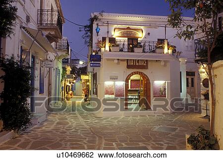 Stock Image -  Paros, Greece, Greek Islands, Parikia, Cyclades, Europe, Shops along the narrow pedestrian streets in Plateia Mavrogenous in the evening in the town of Parikia on Paros Island.. Fotosearch