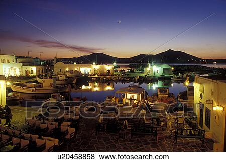 Stock Photo -  Paros, Greek Islands, Naoussa, Cyclades, Greece, Europe, Outdoor cafT on the waterfront on Naoussa Harbor in the evening on Paros Island on the Aegean Sea.. Fotosearch