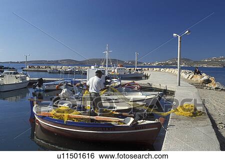 Stock Photograph -  Paros, Greek Islands, Parikia, Cyclades, Greece, Europe, Fisherman pulling net onto fishing boat docked in the harbor of Parikia on Paros Island on the Aegean Sea.. Fotosearch