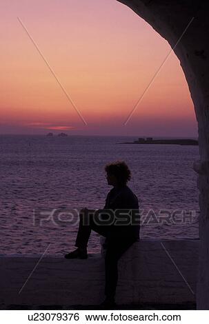 Paros, Greek Islands, Parikia, Cyclades, Greece, Europe, Woman watching the sunset over the Aegean Sea from the terrace of a whitewashed church in the town of Parikia on Paros Island. View Large Photo Image Stock Photograph - Paros, Greek Islands, Parikia, Cyclades, Greece, Europe, Woman watching the sunset over the Aegean Sea from the terrace of a whitewashed church in the town of Parikia on Paros Island.. Fotosearch
