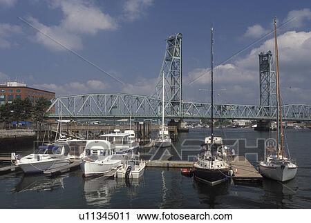 Stock Image -  Portsmouth, NH, New Hampshire, Boats docked along the Piscataqua River in Portsmouth. View of Memorial Bridge crossing the Piscataqua River.. Fotosearch