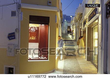 Stock Image -  Santorini, Greek Islands, Fira, Cyclades, Greece, Europe, Shops and boutiques along a narrow pedestrian street in the village of Fira in the evening on Santorini Island on the Aegean Sea. . Fotosearch