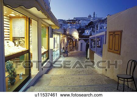 Santorini, Greek Islands, Fira, Cyclades, Greece, Europe, Shops and boutiques along a narrow pedestrian street in the village of Fira in the evening on Santorini Island on the Aegean Sea. View Large Photo Image Stock Image - Santorini, Greek Islands, Fira, Cyclades, Greece, Europe, Shops and boutiques along a narrow pedestrian street in the village of Fira in the evening on Santorini Island on the Aegean Sea. . Fotosearch