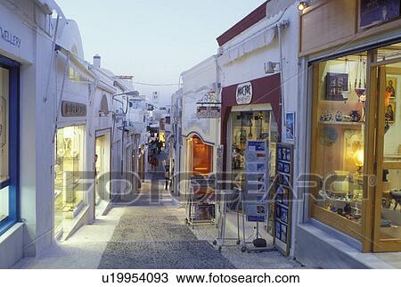 Santorini, Greek Islands, Fira, Cyclades, Greece, Europe, Shops and boutiques along a narrow pedestrian street in the village of Fira in the evening on Santorini Island on the Aegean Sea. View Large Photo Image Stock Image - Santorini, Greek Islands, Fira, Cyclades, Greece, Europe, Shops and boutiques along a narrow pedestrian street in the village of Fira in the evening on Santorini Island on the Aegean Sea. . Fotosearch
