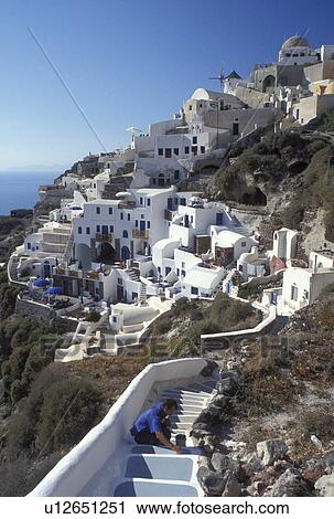 Stock Image -  Santorini, Greek Islands, Oia, Cyclades, Greece, Europe, Man painting steps in the village of Oia on the steep hillside of Santorini Island on the Aegean Sea.. Fotosearch