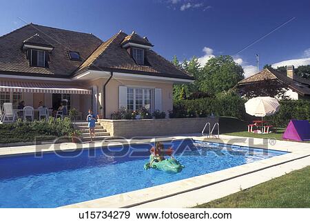 swimming pool, Switzerland, Vaud, Rolle, La Cote, A 6 year old girl floats on an inflatable alligator in her swimming pool at home in Rolle in the Canton of Vaud. View Large Photo Image Stock Photo -  swimming pool, Switzerland, Vaud, Rolle, La Cote, A 6 year old girl floats on an inflatable alligator in her swimming pool at home in Rolle in the Canton of Vaud.. Fotosearch
