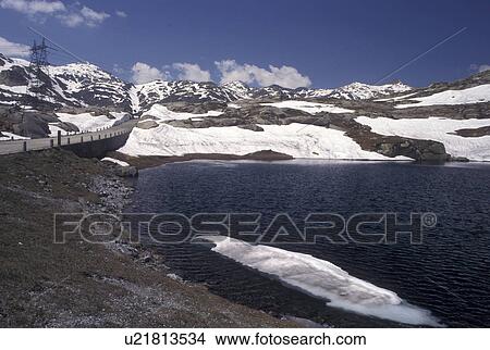 Picture -  Switzerland, Alps, Ticino, Saint Gotthard Pass Road, Snow on the summit of St. Gotthard Mountain Pass in the scenic Swiss Alps in the summer.. Fotosearch