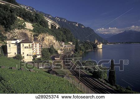 Switzerland, Montreux, Alps, Lake Geneva, Vaud, Train tracks wind along the lakeshore of Lac Leman with a scenic view of the Alps and the Chateau de Chillon in the Canton of Vaud. View Large Photo Image Picture - Switzerland, Montreux, Alps, Lake Geneva, Vaud, Train tracks wind along the lakeshore of Lac Leman with a scenic view of the Alps and the Chateau de Chillon in the Canton of Vaud. . Fotosearch