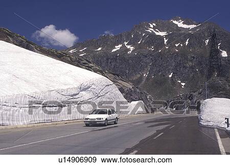 Switzerland, Ticino, Alps, Saint Gotthard Pass Road, Snow piled on the side of the mountain road at the summit of St. Gotthard Mountain Pass in the scenic Swiss Alps in the summer. View Large Photo Image Stock Photo - Switzerland, Ticino, Alps, Saint Gotthard Pass Road, Snow piled on the side of the mountain road at the summit of St. Gotthard Mountain Pass in the scenic Swiss Alps in the summer.. Fotosearch