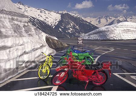 Switzerland, Valais, Grimsel Pass, Alps, Four colorful motorbikes, red, blue, green and yellow, parked on the side of the mountain road piled with snow on the summit of Grimsel Pass the Swiss Alps in the Canton of Valais in the summer (July). View Large Photo Image Stock Photography - Switzerland, Valais, Grimsel Pass, Alps, Four colorful motorbikes, red, blue, green and yellow, parked on the side of the mountain road piled with snow on the summit of Grimsel Pass the Swiss Alps in the Canton of Valais in the summer (July).. Fotosearch