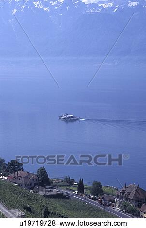 Switzerland, vineyards, Vaud, Lavaux, Lake Geneva, Scenic view of an excursion steamer boat cruising along the lakeshore of Lac Leman from the steep slopes of the vineyards of Lavaux in the Canton of Vaud. The Alps can be seen in the distance. View Large Photo Image Stock Photo - Switzerland, vineyards, Vaud, Lavaux, Lake Geneva, Scenic view of an excursion steamer boat cruising along the lakeshore of Lac Leman from the steep slopes of the vineyards of Lavaux in the Canton of Vaud. The Alps can be seen in the distance.. Fotosearch