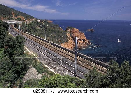 Stock Photo -  TGV, Massif de l' Esterel, Cote d' Azur, Provence, France, Var, Europe, The TGV high-speed train track along the red rocky coastline of the Corniche de l' Esterel on the Mediterranean Sea.. Fotosearch