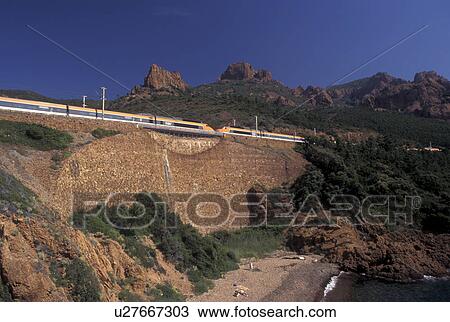 Stock Image -  TGV, train, Massif de l' Esterel, Cote d' Azur, Provence, France, Var, Europe, The TGV high-speed train travels along the red rocky coastline of the Corniche de l' Esterel on the Mediterranean Sea.. Fotosearch