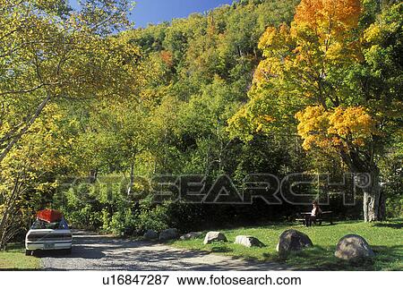 Stock Photo -  The Adirondacks, NY, New York, Lake Placid, White car with red canoe parked at picnic area in Lake Placid in the autumn. . Fotosearch