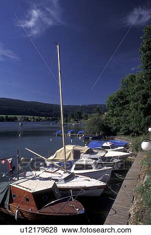 Stock Photo -  Vallee de Joux, Switzerland, Vaud, Boats docked along the lakefront of Lac de Joux in Le Pont in the Jura mountain region.. Fotosearch