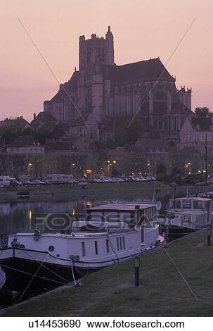Stock Image -  Auxerre, Burgundy, France, Yonne, Bourgogne, Europe, wine region, View of the Cathedral St. Etienne and house barges along the Yonne River at sunset in the city of Auxerre.. Fotosearch