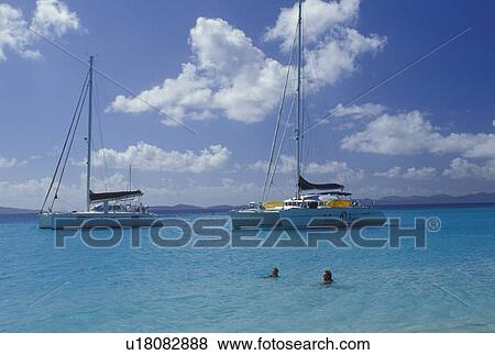 beach, Jost Van Dyke, British Virgin Islands, Caribbean, BVI, A couple swims near two catamarans anchored in White Bay off Jost Van Dyke Island on the Caribbean Sea. View Large Photo Image Stock Photo - beach, Jost Van Dyke, British Virgin Islands, Caribbean, BVI, A couple swims near two catamarans anchored in White Bay off Jost Van Dyke Island on the Caribbean Sea.. Fotosearch