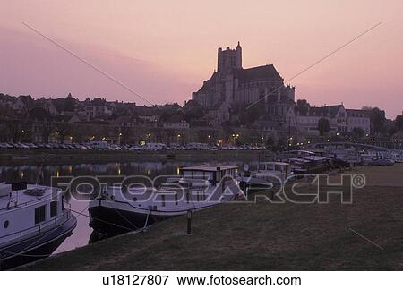 Stock Photo -  Burgundy, Auxerre, France, Yonne, Bourgogne, Europe, wine region, View of the Cathedral St. Etienne and house barges along the Yonne River at sunset in the city of Auxerre.. Fotosearch