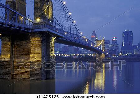 Stock Photography -  Cincinnati, OH, Ohio, John A. Roebling Bridge, downtown skyline along the Ohio River, evening. Fotosearch