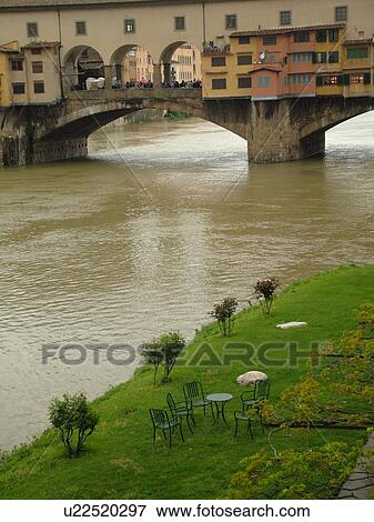 Stock Photo -  Florence, Italy, Firenza, Toscana, Tuscany, Europe, Ponte Vecchio, a bridge lined with shops, crosses the River Arno in the city of Florence.. Fotosearch