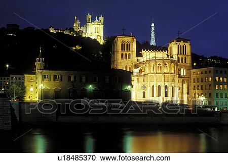 Stock Image -  France, Lyon, Rhone-Alpes, Europe, Cathedral Saint Jean (below) and Basilique Notre Dame de Fourviere (above) illuminated at night along the Saone River in Lyon.. Fotosearch