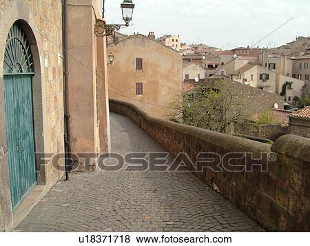 Stock Photo -  Italy, Lazio, Tuscania, Europe, Narrow cobblestone street in the village of Tuscania.. Fotosearch