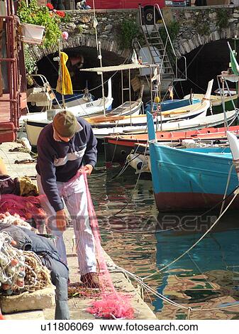 Liguria, Italy, Camogli, Riviera di Levante, Ligurian Riviera, Europe, Fisherman preparing this fishing nets along the waterfront of the fishing port in the resort town of Camogli along the Ligurian Sea. View Large Photo Image Stock Photo - Liguria, Italy, Camogli, Riviera di Levante, Ligurian Riviera, Europe, Fisherman preparing this fishing nets along the waterfront of the fishing port in the resort town of Camogli along the Ligurian Sea.. Fotosearch