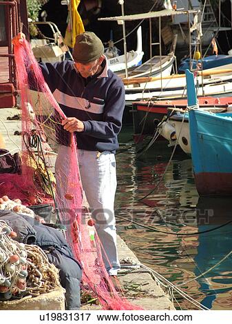Liguria, Italy, Camogli, Riviera di Levante, Ligurian Riviera, Europe, Fisherman preparing this fishing nets along the waterfront of the fishing port in the resort town of Camogli along the Ligurian Sea. View Large Photo Image Stock Photo - Liguria, Italy, Camogli, Riviera di Levante, Ligurian Riviera, Europe, Fisherman preparing this fishing nets along the waterfront of the fishing port in the resort town of Camogli along the Ligurian Sea.. Fotosearch