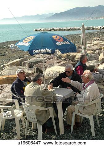 Liguria, Italy, Sestri Levante, Riviera di Levante, Ligurian Riviera, Europe, Senior Italian men playing cards at a table along the beach in the resort town of Sestri Levante on the Ligurian Sea. View Large Photo Image Stock Photo - Liguria, Italy, Sestri Levante, Riviera di Levante, Ligurian Riviera, Europe, Senior Italian men playing cards at a table along the beach in the resort town of Sestri Levante on the Ligurian Sea.. Fotosearch