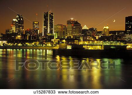 Stock Image -  Montreal, Canada, Quebec, Skyline of downtown Montreal along the St. Lawrence River (Fleuve Saint-Laurent) in the evening.. Fotosearch